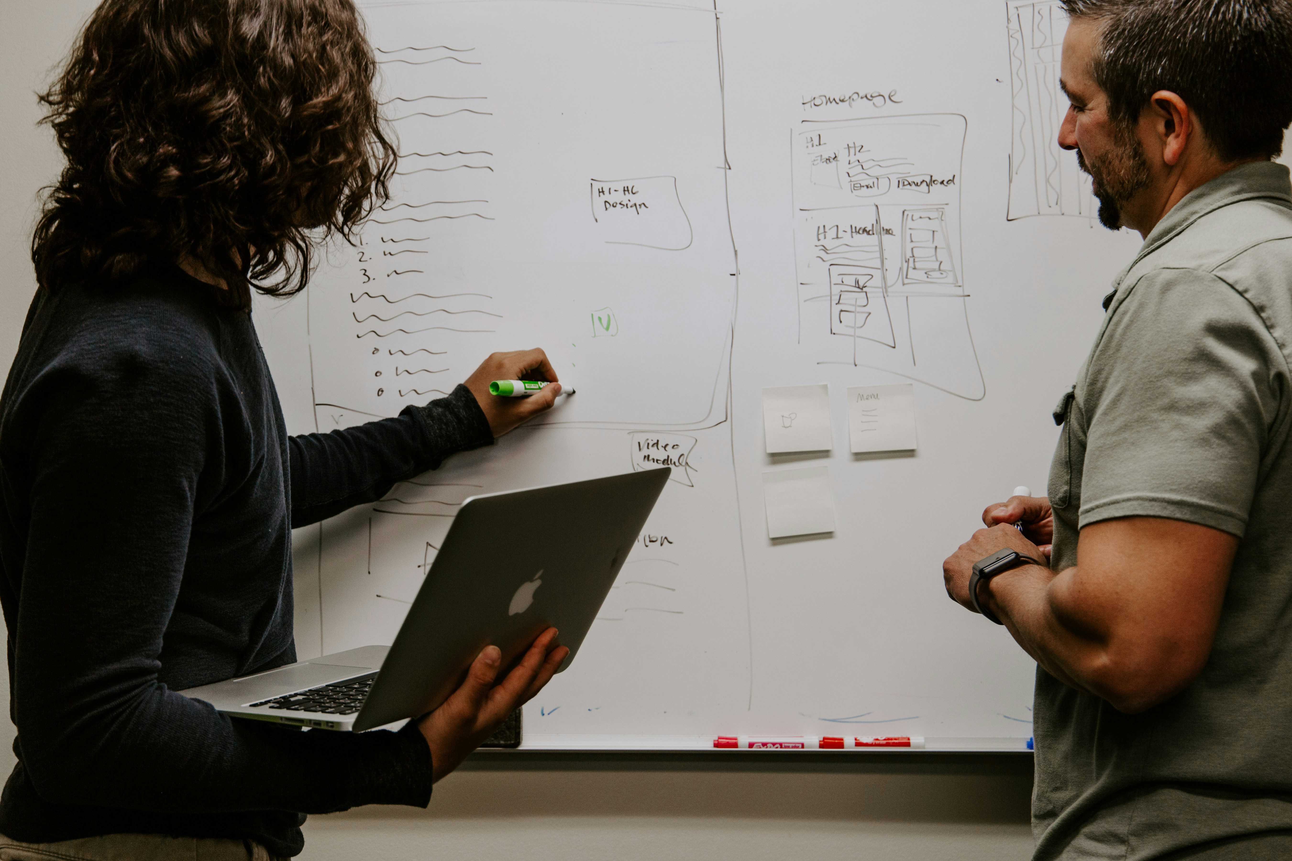 Two professionals collaborating on UX planning at a whiteboard.
